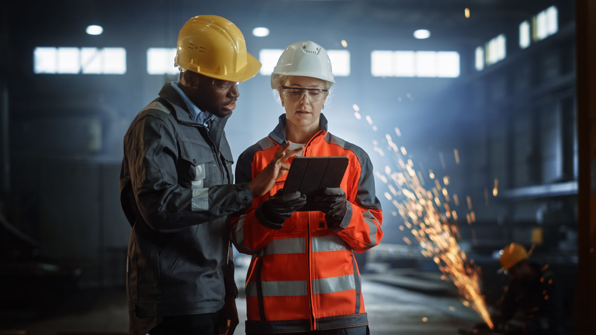 Engineers Stand in Steel Metal Manufacturing Factory, Use Digital Tablet Computer and Have a Discussion